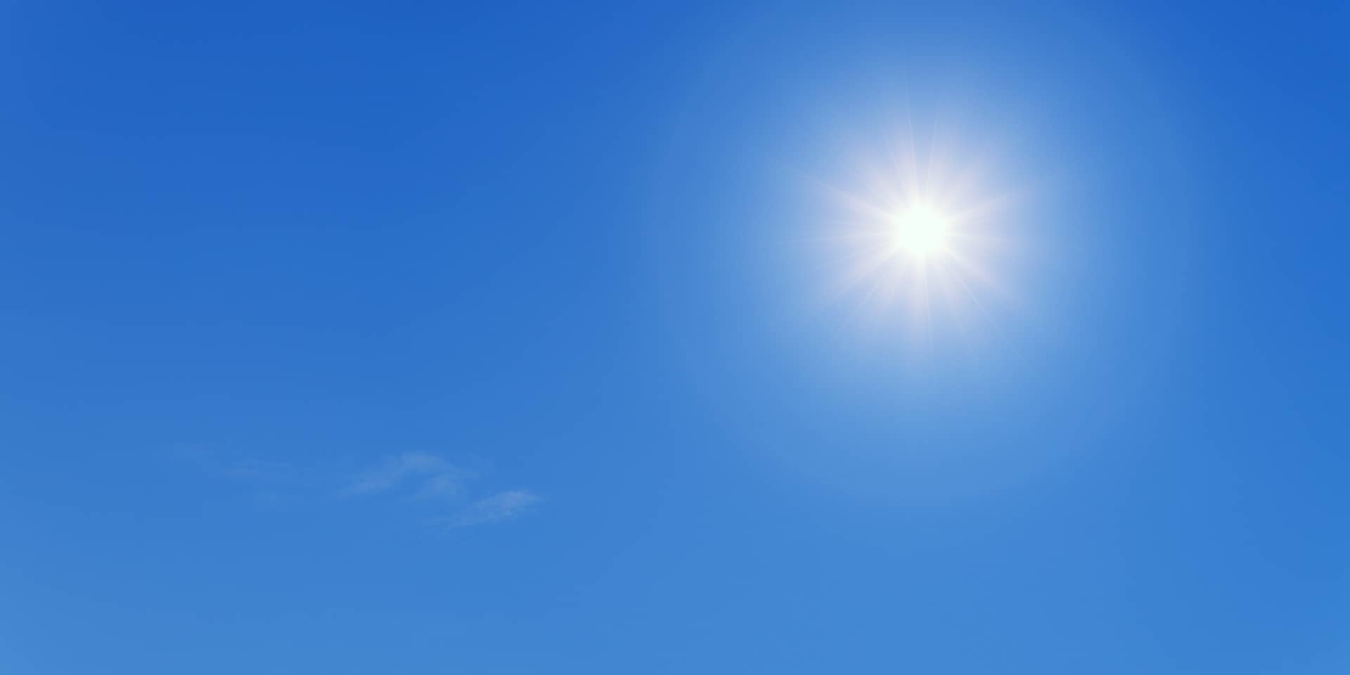A clear blue sky with a bright sun shining, ideal for solar panels, and a small, wispy cloud on the bottom left.