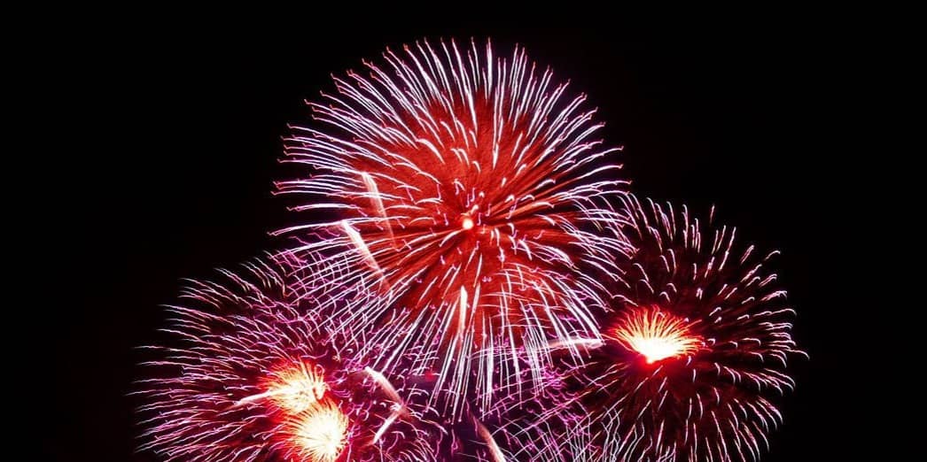 Colourful fireworks with red, purple, and green bursts against a dark night sky.