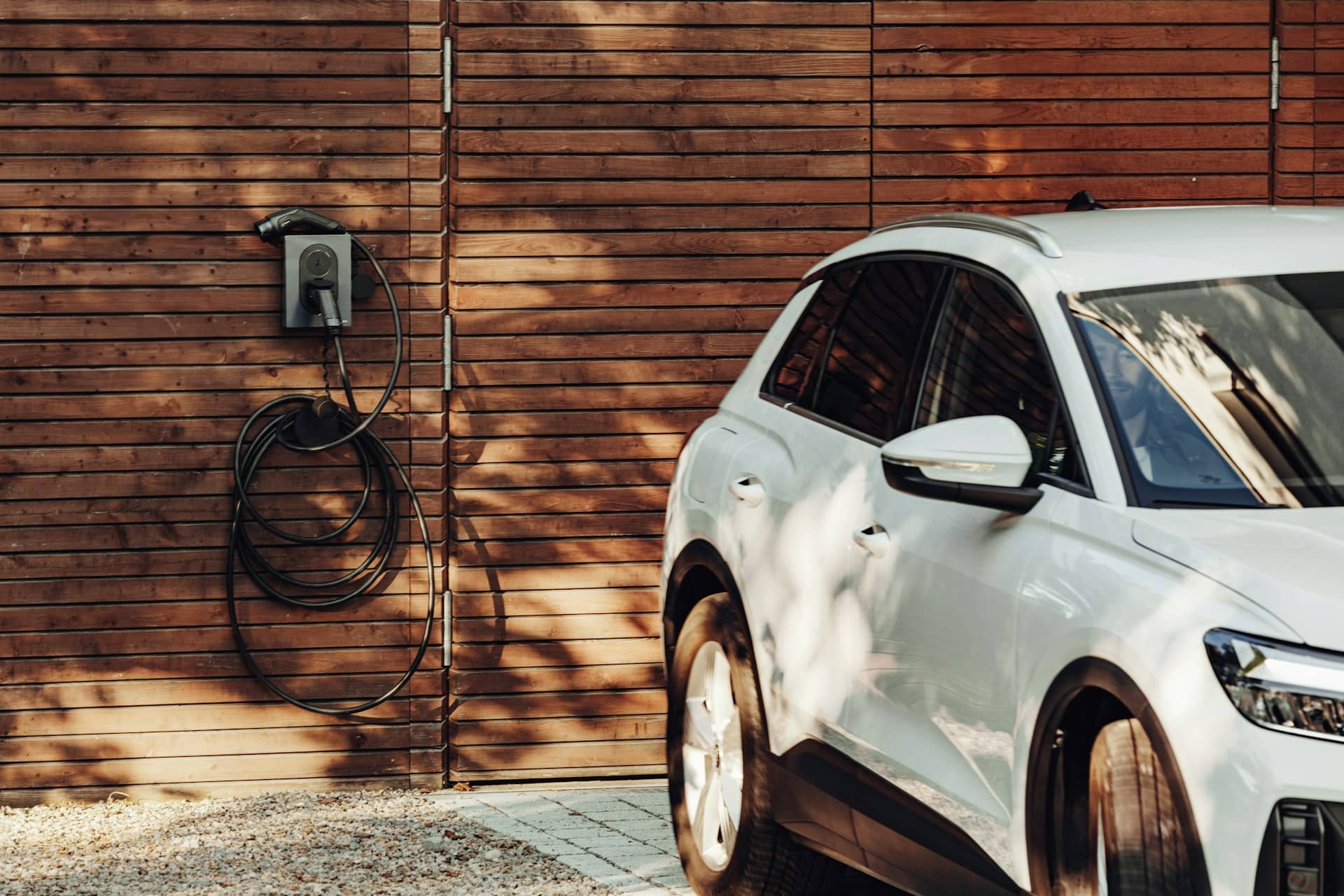 An electric car charging with a wall-mounted charger on a wooden panel.
